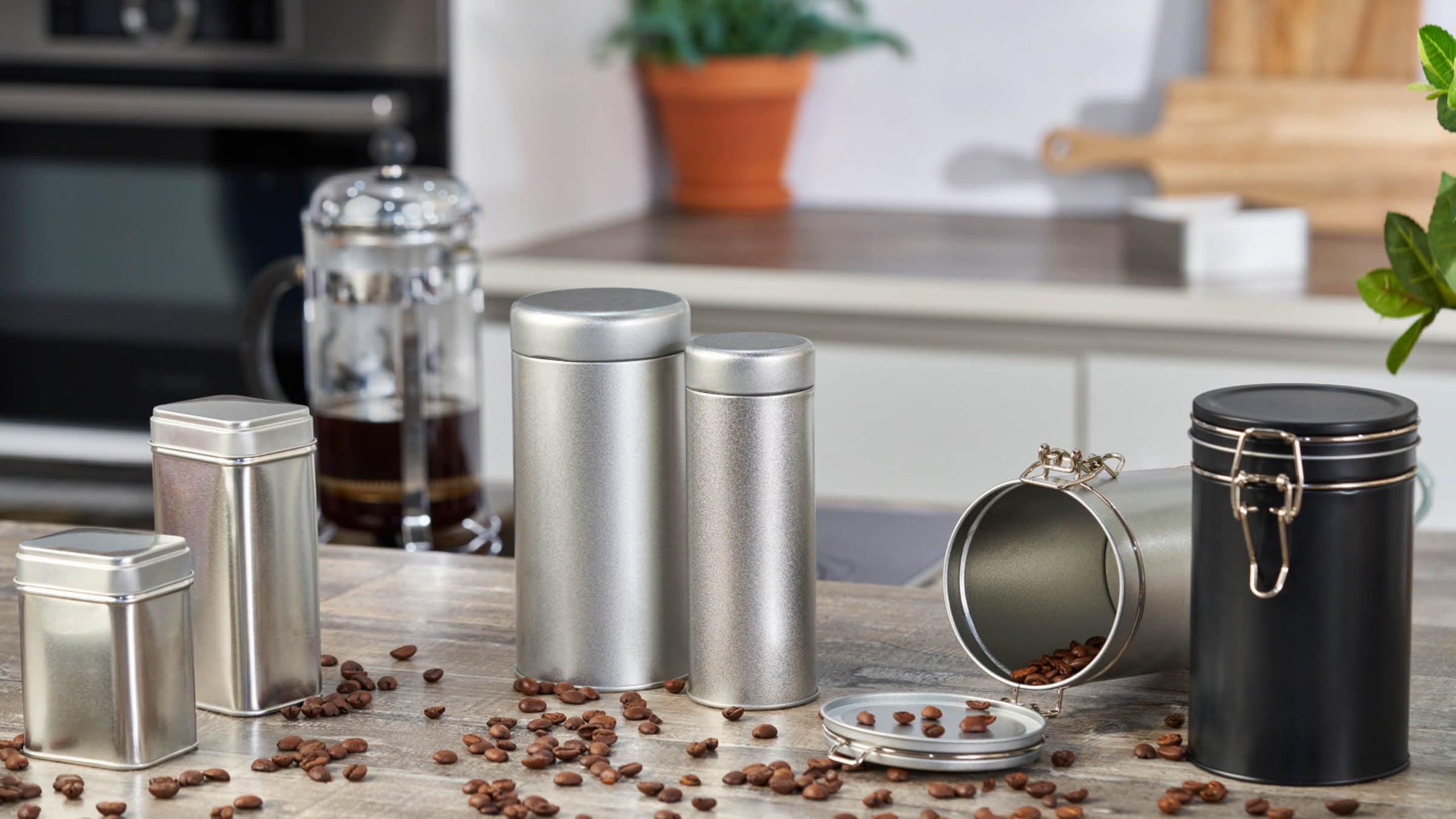 Een assortiment van metalen containers gebruikt voor koffie, specerijen, en kruiden in een keuken omgeving.