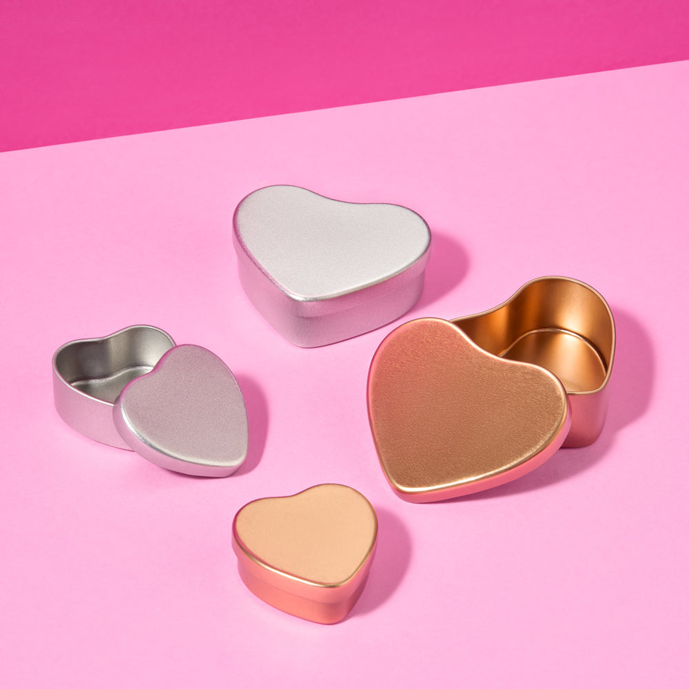 Collectie hartvormige blikken in zilver en roségoud op roze achtergrond