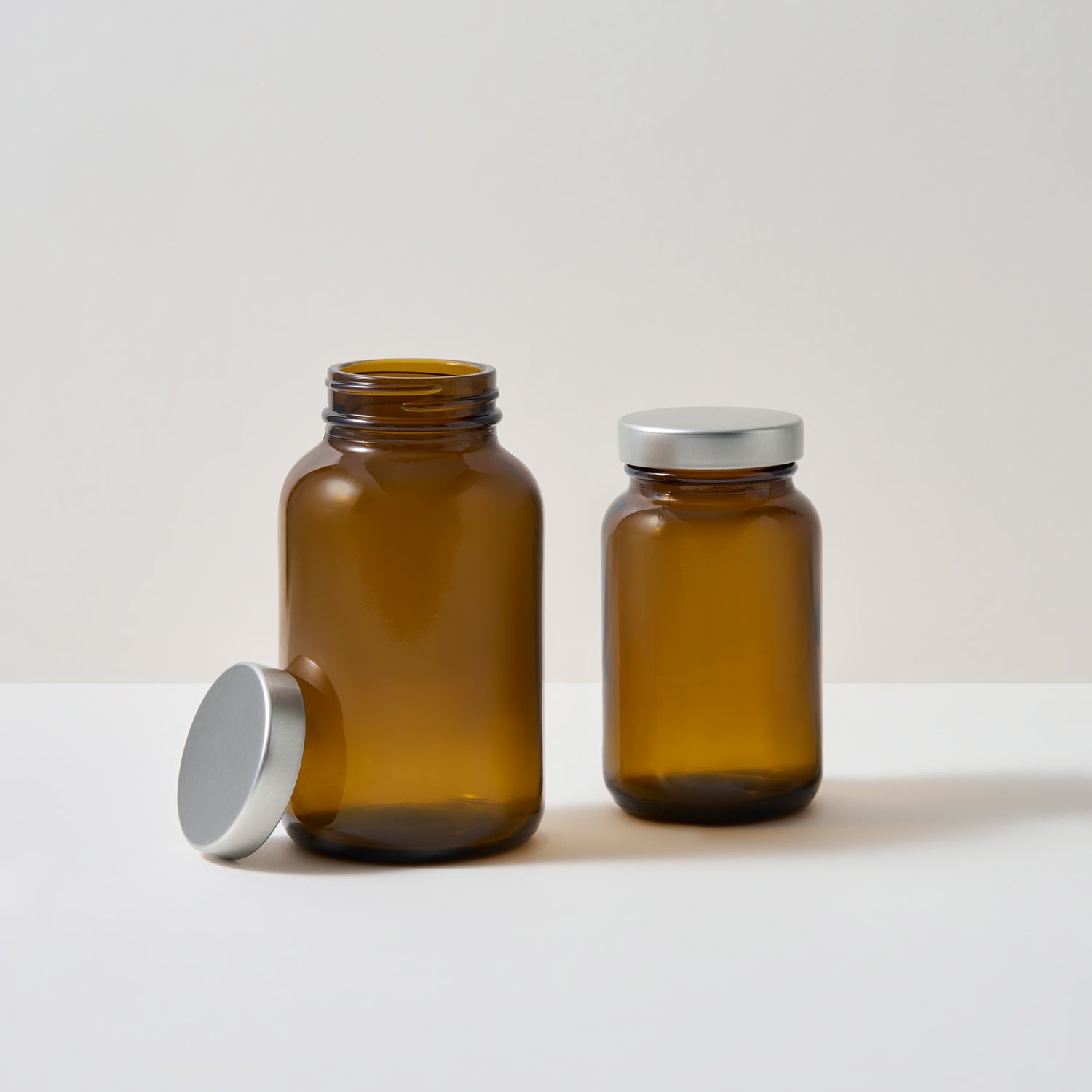 Amberkleurige glazen potten voor voedingssupplementen tegen een witte achtergrond 